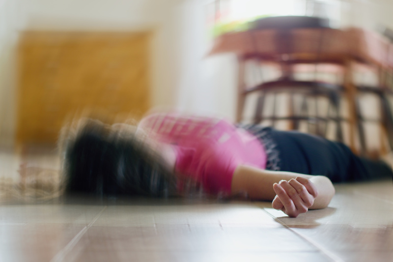 Eine Frau liegt mit einem epileptischen Anfall am Boden