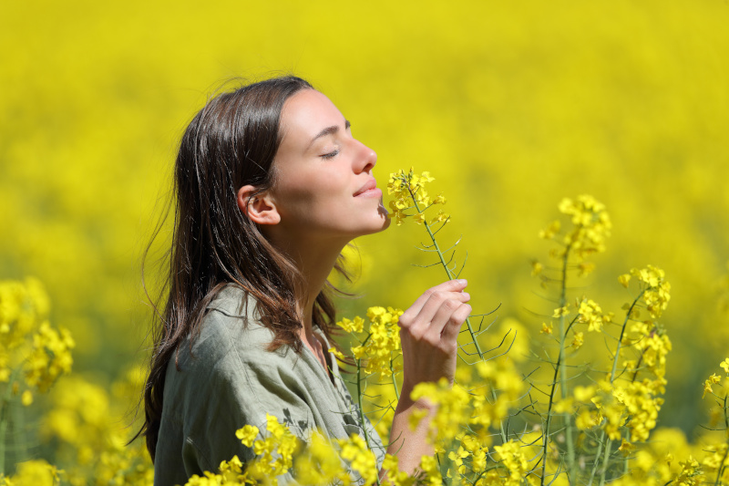 Eine junge Frau riecht an einer gelben Blume